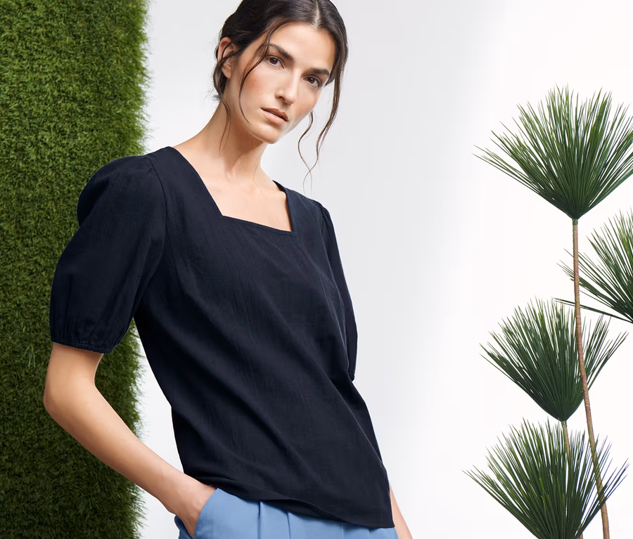 Frau posiert in blauer Bluse und blauer Hose.