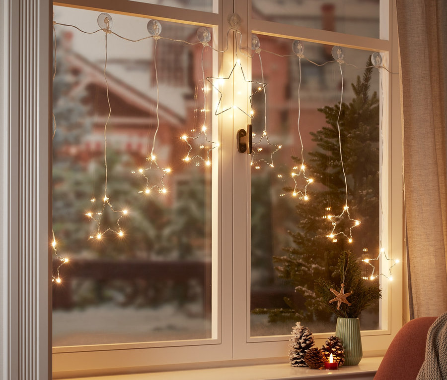 Am Fenster hängt ein LED-Lichtervorhang in Sternform.