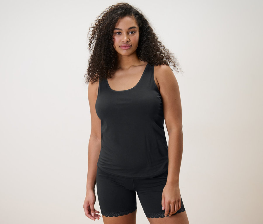 Frau trägt schwarzes Hemdchen und 2 Radler-Shorts.