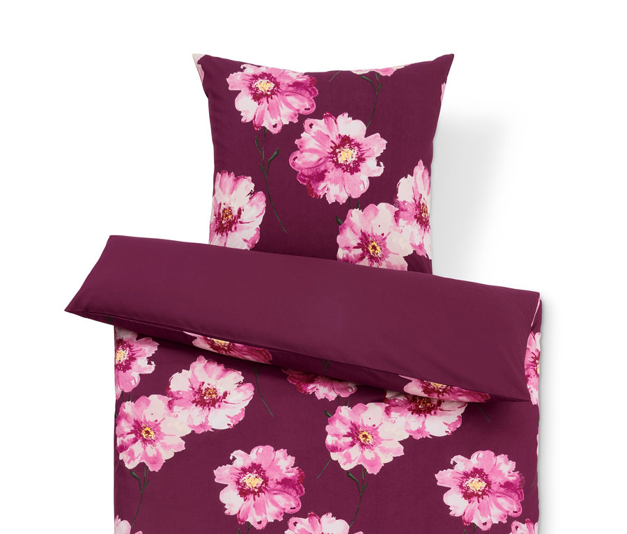 Violette Bettwäsche mit Blumenmuster und einfarbigem violettem Kissen.
