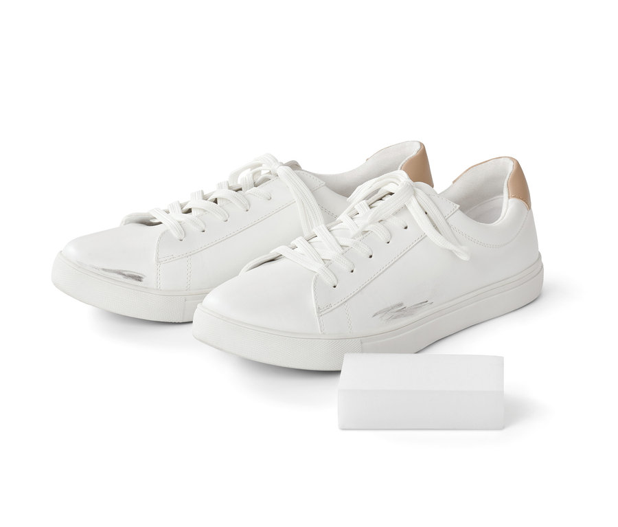 Zwei weiße Turnschuhe mit Schmutzstreifen und eine Packung mit 10 Schmutzradierern.