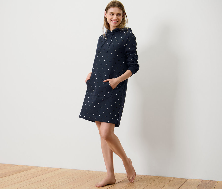 Frau posiert in einem Loungewear-Kleid mit Punkten.