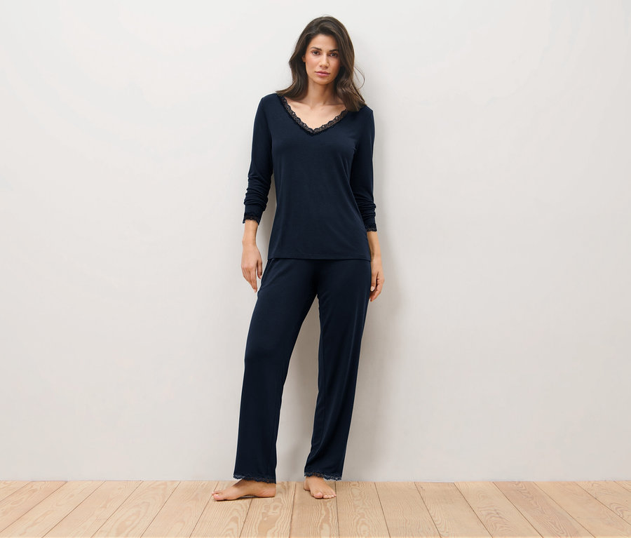 Frau steht auf einem Holzboden und trägt einen dunkelblauen Pyjama.