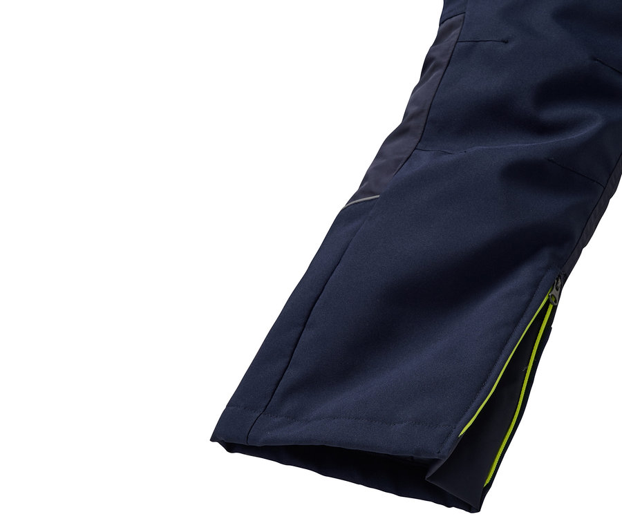 Detail einer Hose mit geöffnetem Reißverschluss und limettengrüner Bordüre.