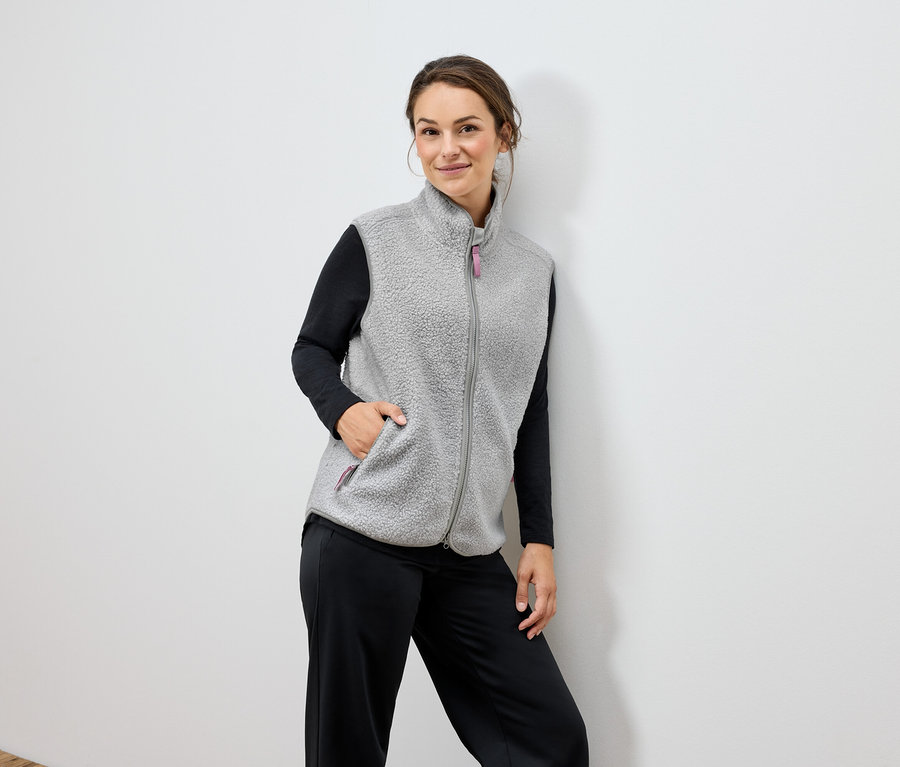 Frau trägt eine graue Fleeceweste und eine schwarze Hose.