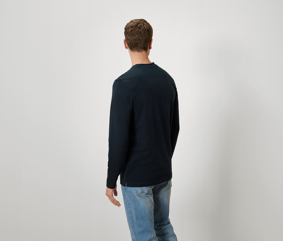 Mann von hinten in marineblauem Langarmshirt und blauen Jeans.
