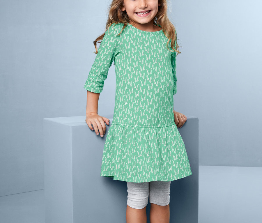 Ein lächelndes Mädchen posiert in einem Jerseykleid mit floralem Alloverprint.