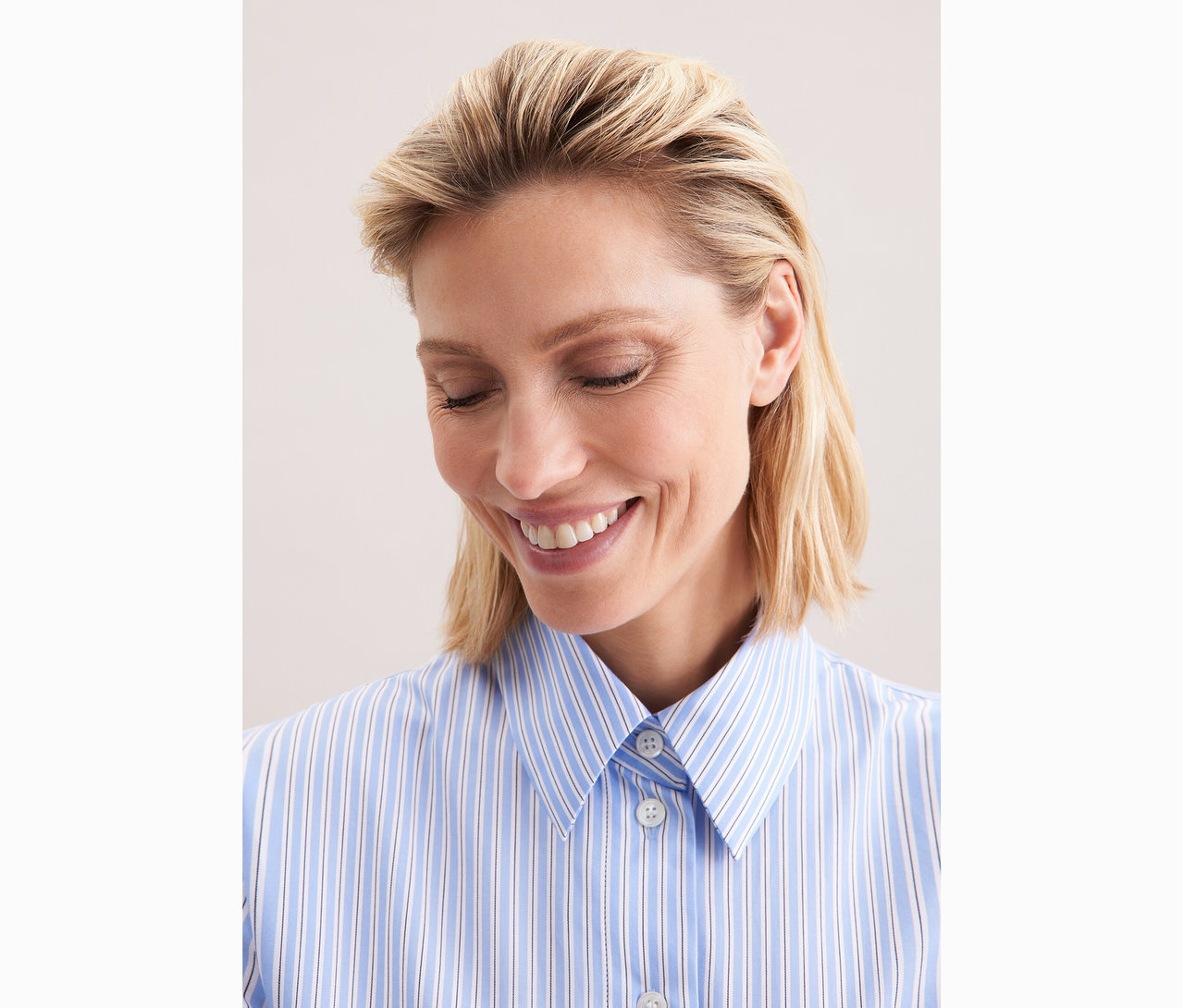 Frau trägt eine blau-weiss gestreifte Seidensticker Oversize-Hemdbluse.