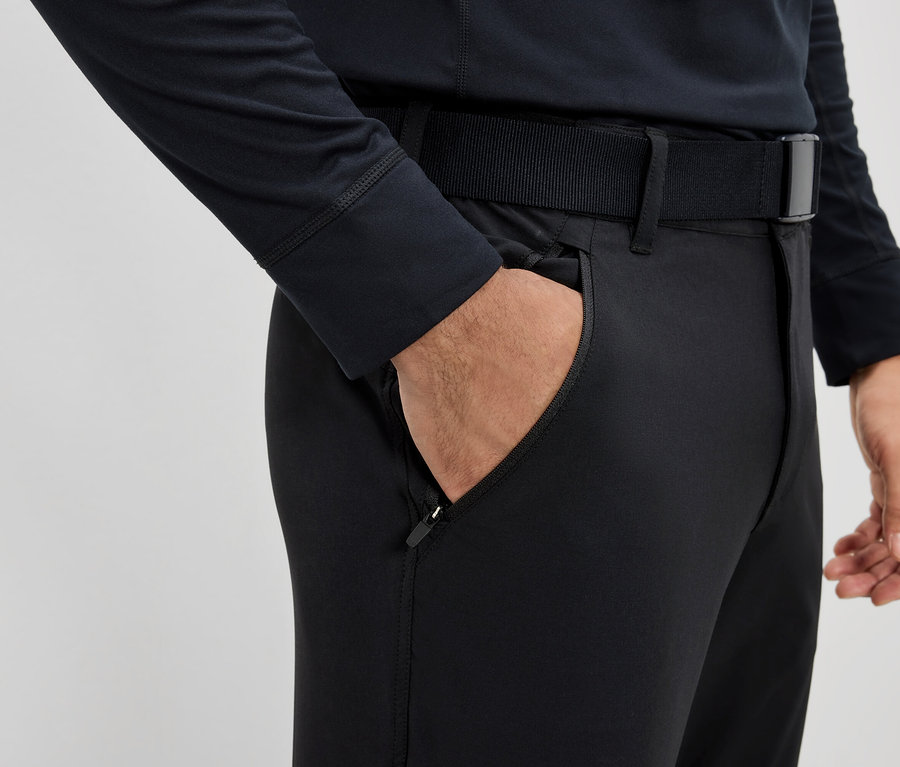 Mann hat Hand in der Tasche einer schwarzen Hose mit Gürtel.