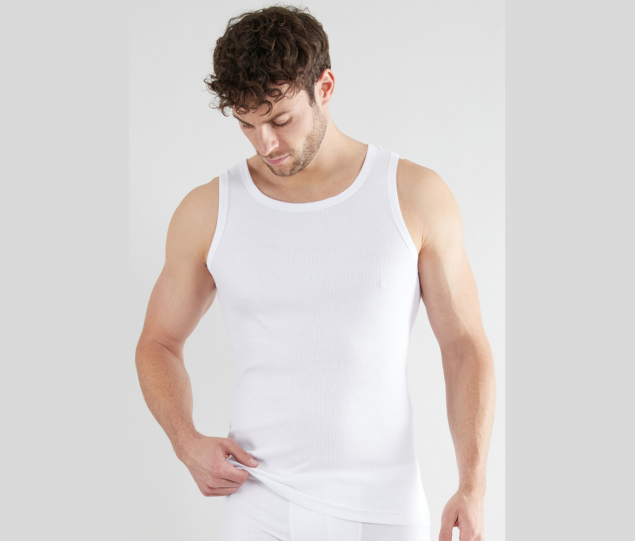 Mann trägt ein weißes Rippenunterhemd und Unterhose.