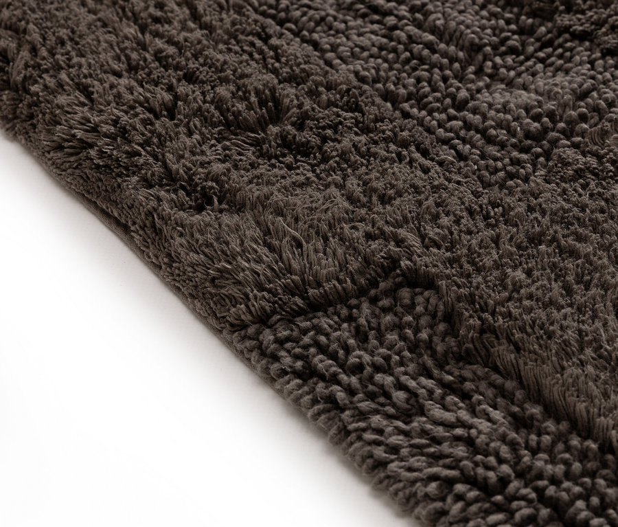 Nahaufnahme eines dunkelbraunen, zotteligen Teppichs.