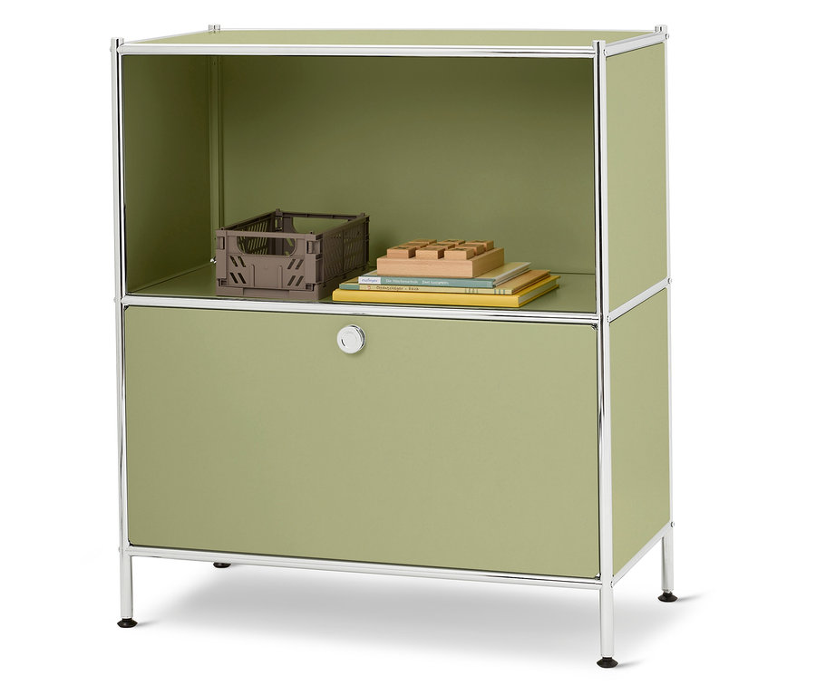 Ein grüner Schrank mit einem silbernen Rahmen steht auf einem weißen Hintergrund. Auf der oberen Ablage befinden sich eine braune Kiste, Bücher und ein Holzspielzeug.