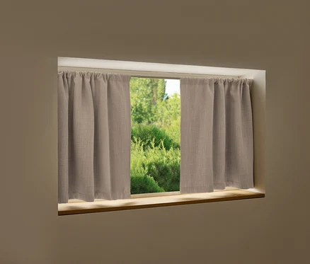 Ein Fenster mit beigen Vorhängen und Blick auf grüne Vegetation.