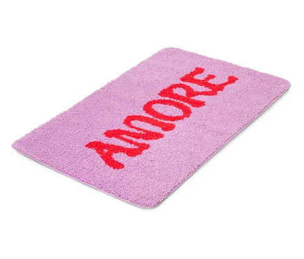 Ein lilafarbener Badteppich mit dem roten Wort "AMORE" darauf.