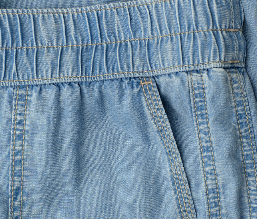 Detailansicht einer hellblauen Hose mit elastischem Bund und einer aufgesetzten Tasche.