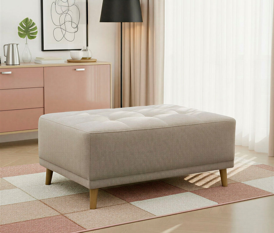 Ein beiger, getufteter Ottoman mit Holzbeinen steht auf einem karierten Teppich mit rosa, beigen und weißen Quadraten. Im Hintergrund befinden sich eine rosa Kommode mit Pflanze, Kanne und gerahmtem Bild, eine schwarze Stehlampe und helle Vorhänge.