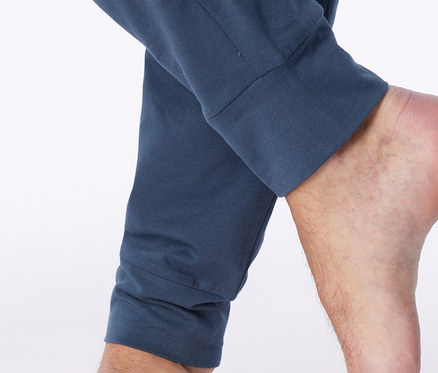 Nahaufnahme eines nackten Fußes und Unterschenkels, mit einer blauen Hose mit Bündchen am Knöchel.