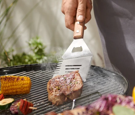 Mann grillt Steak mit BBQ-Multitool.