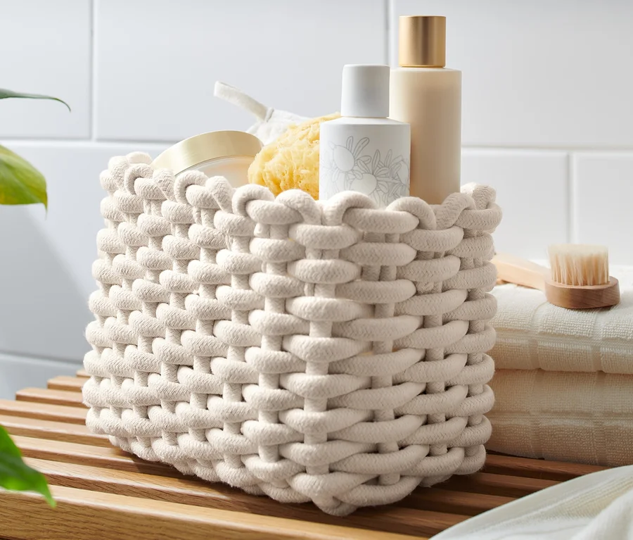 Ein geflochtener Korb steht auf einem Holzregal neben gefalteten Handtüchern.