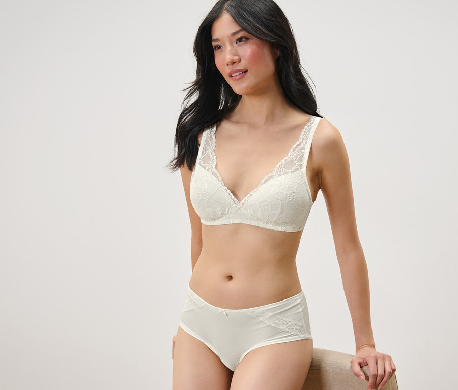 Frau posiert in BH mit Spitze und 2 Pantys, creme.