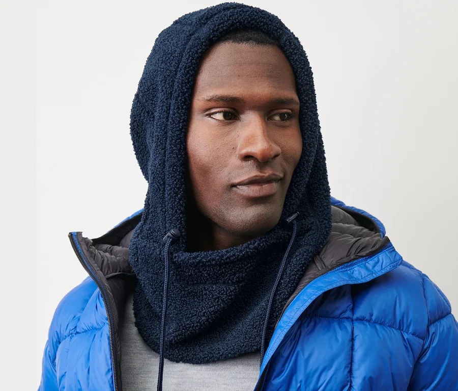 Mann trägt eine Teddy-Kapuze mit Stehkragen und eine blaue Daunenjacke.