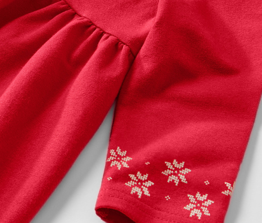 Detailansicht eines Kinder-Sweatkleids in Rot mit langen Ärmeln und Schneeflockenmuster.