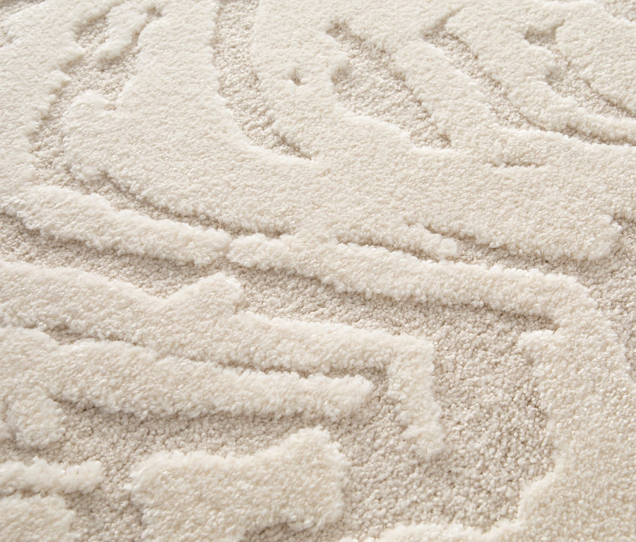 Detailansicht eines cremefarbenen Teppichs »Cosmo« mit Wellenmuster.