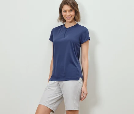 Frau posiert in einem Half-Zip-Sportshirt und Shorts.
