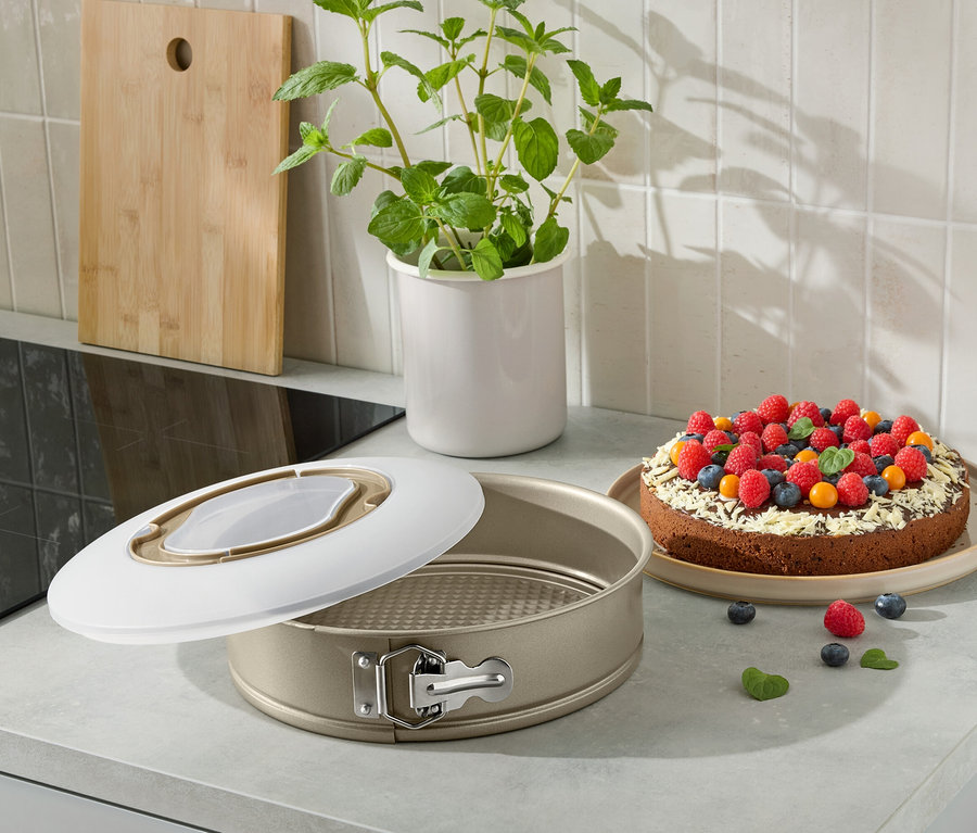 Eine offene Kuchenform mit einem gebackenen Kuchen, der mit Früchten auf einer Küchentheke verziert ist.