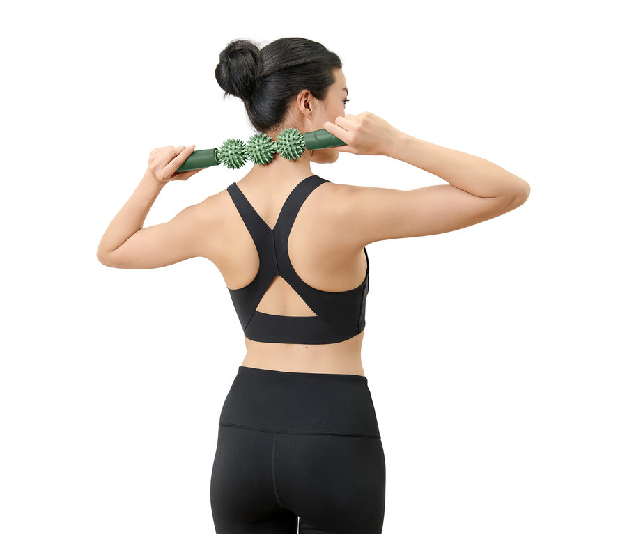 Frau verwendet eine grüne Massagerolle für den Nacken.