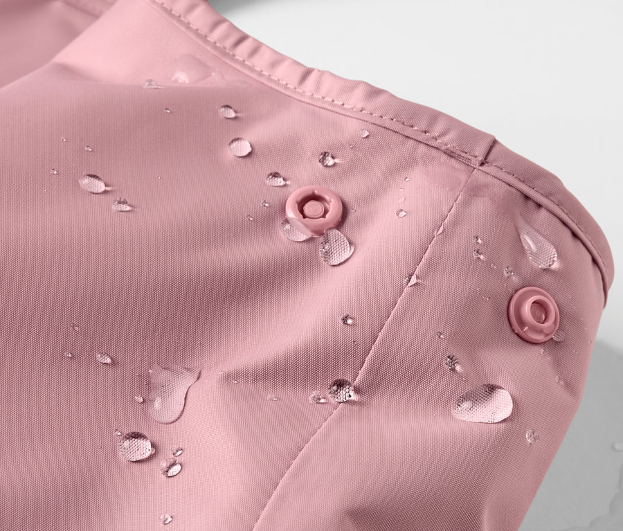 Detailaufnahme einer Kinder-Thermo-Regenhose in Rosa mit Wassertropfen.