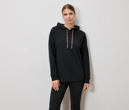 Frau trägt schwarzen Hoodie und Hose.
