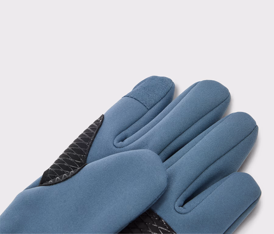 Nahaufnahme eines blauen Handschuhs mit schwarzer Verstärkung an Daumen und Handfläche.