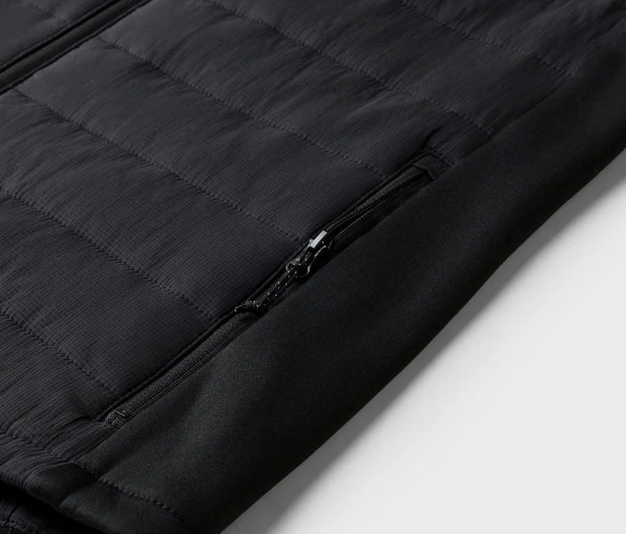 Nahaufnahme einer schwarzen Steppjacke mit Reißverschlusstasche am Ärmel.
