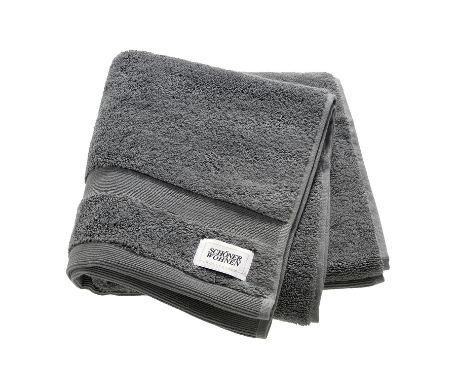 Ein gefaltetes anthrazitfarbenes SCHÖNER WOHNEN-Kollektion Handtuch mit gerippter Borte und Markenetikett.