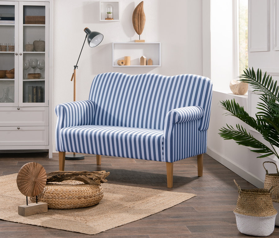 Wohnzimmer mit Möbeln und Dekorationen. Im Vordergrund befindet sich ein Küchensofa "Juuma" mit blauen und weißen Streifen.