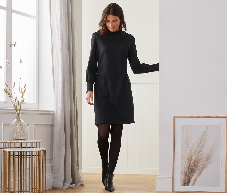 Frau geht in schwarzem Sweatkleid.
