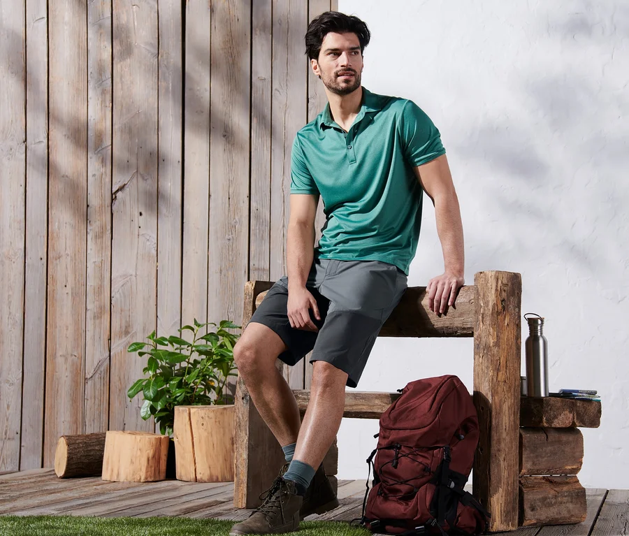 Mann sitzt auf Holzbank, trägt graue Funktionsshorts.