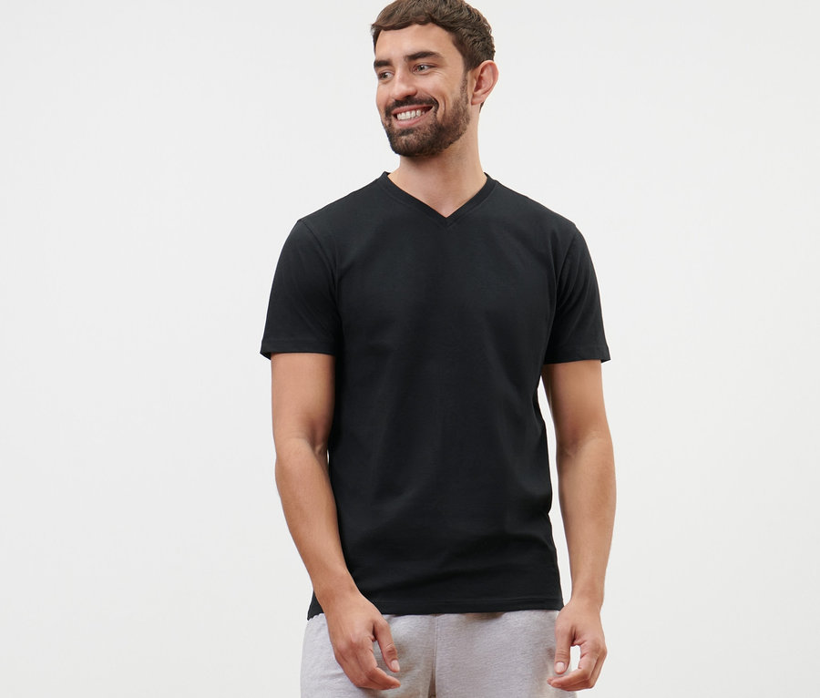 Mann trägt ein schwarzes T-Shirt mit V-Ausschnitt und graue Shorts.
