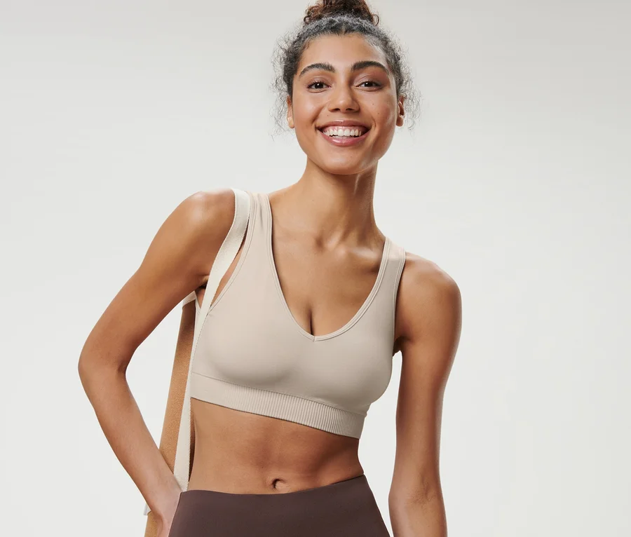 Frau lächelt und trägt ein offwhite Seamless-Sport-Bustier.