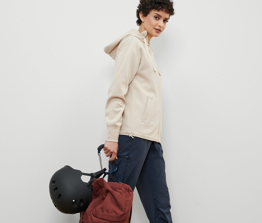 Frau geht und trägt Helm und Rucksack, befestigt mit 2 XXL-Karabinerhaken.