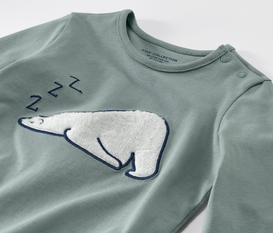 Detailansicht eines Kinder-Pyjamas mit einer aufgenähten schlafenden Eisbär-Applikation.
