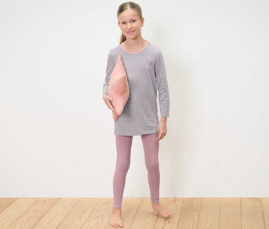 Mädchen hält rosa Kissen und trägt 2 Kinder-Pyjamas.