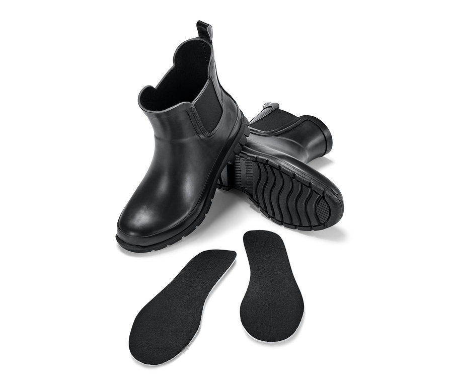 Zwei schwarze Kinder-Regen-Chelseaboots und zwei schwarze Einlegesohlen auf weißem Hintergrund.