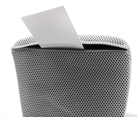 Ein weißes Blatt Papier, das in einen grauen Topstar Sitness »Home S'cool« Bürostuhl aus Netzstoff gesteckt wird.