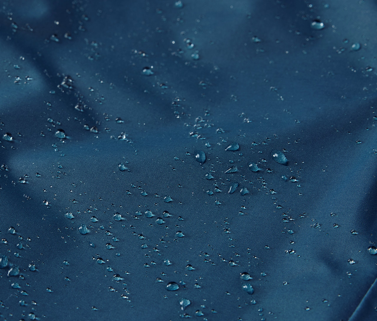 Detailaufnahme einer Kinder-Thermo-Regenhose mit Wassertropfen auf der Oberfläche.