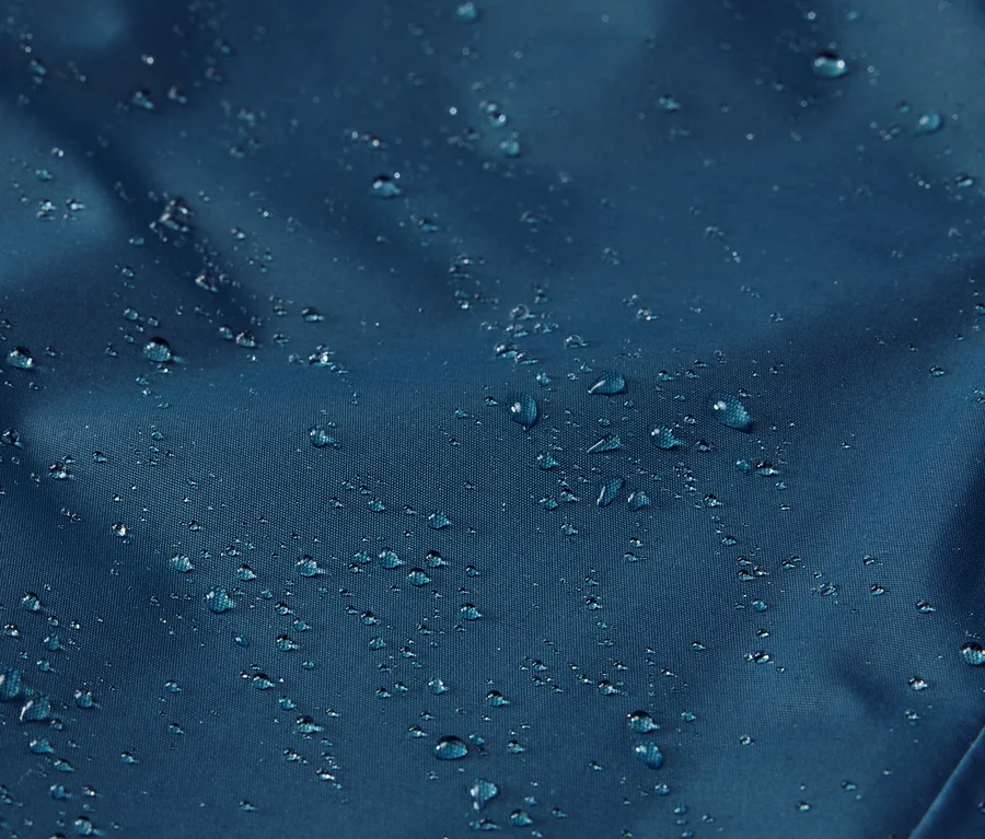 Detailaufnahme einer Kinder-Thermo-Regenhose mit Wassertropfen auf der Oberfläche.