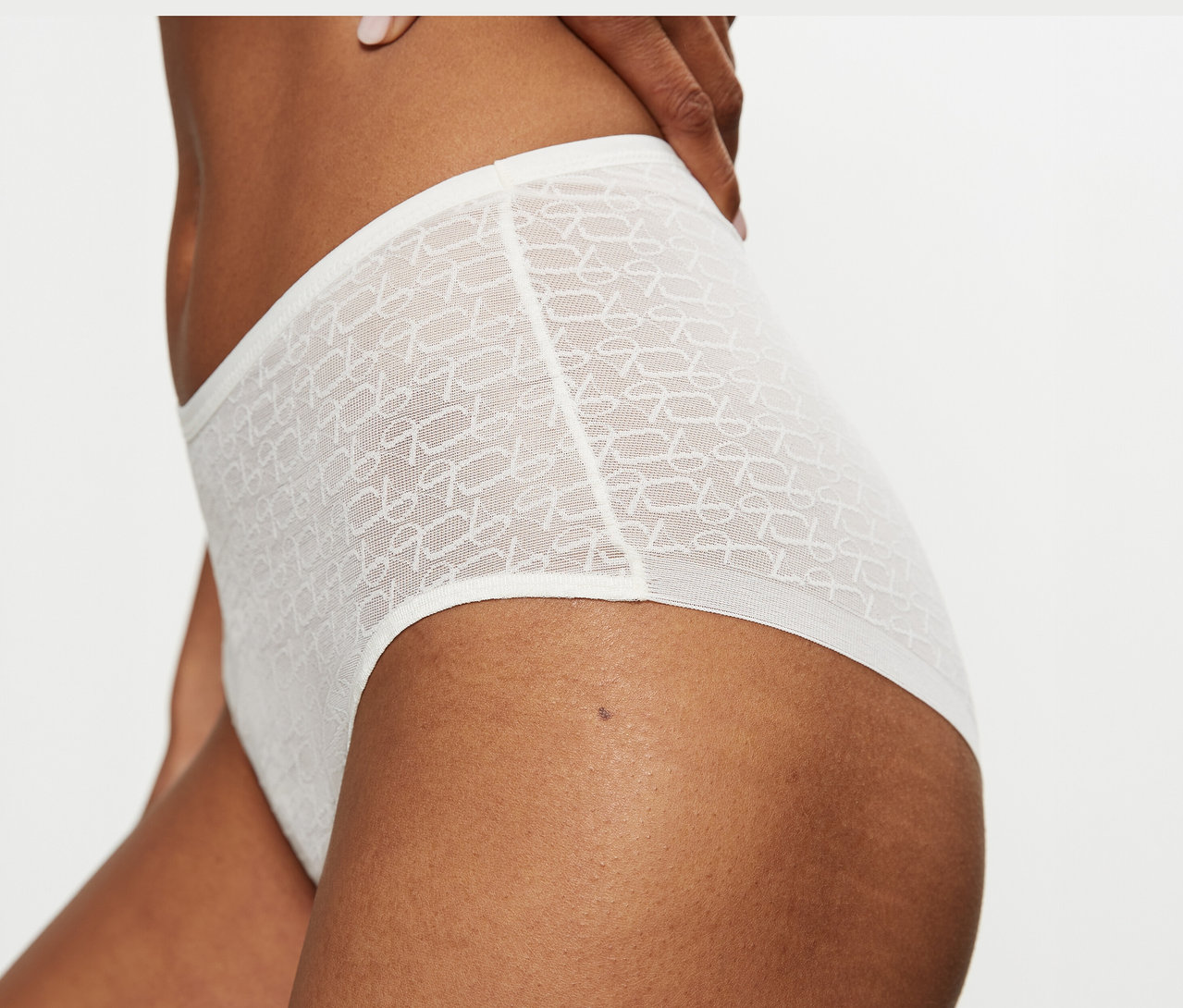 Nahaufnahme einer Person, die einen hochgeschnittenen, transparenten Triumph Signature Sheer Maxi EX Slip in Ecru White mit Muster trägt.