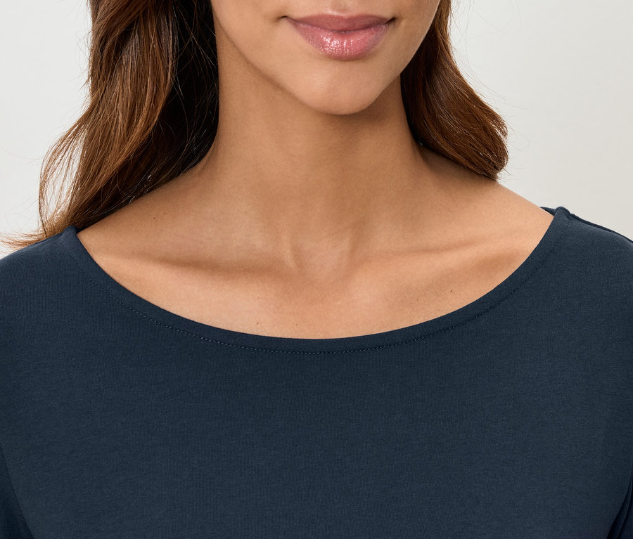 Detailaufnahme eines dunkelblauen Damenoberteils mit langen Ärmeln, das von den Schultern bis zur Oberlippe gezeigt wird.