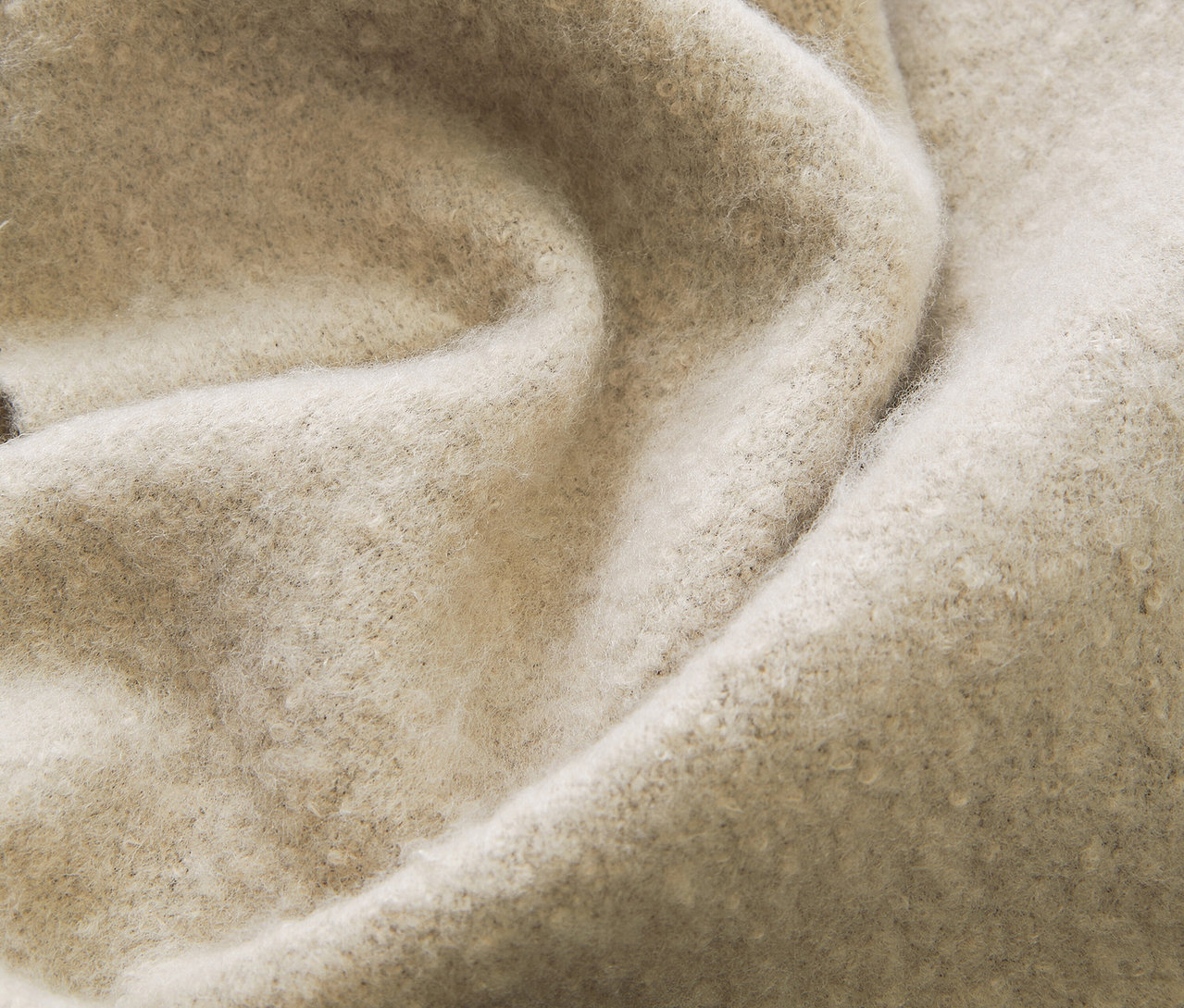 Nahaufnahme eines strukturierten, cremefarbenen Stoffes mit dezenten Falten.